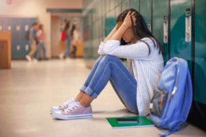 An older child sits in front of their locker