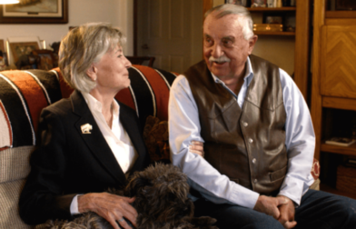 Dr. Bonnie Snyder sits on a couch next to her husband. She's a mesothelioma survivor.