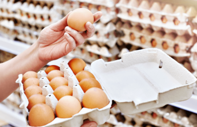 A woman feels eggs from a shelf, presumably to assess their freshness.