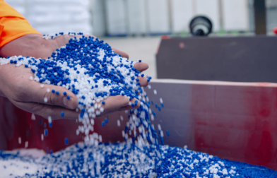 Image of a person holding up blue and white plastic granules representing PFAS chemicals